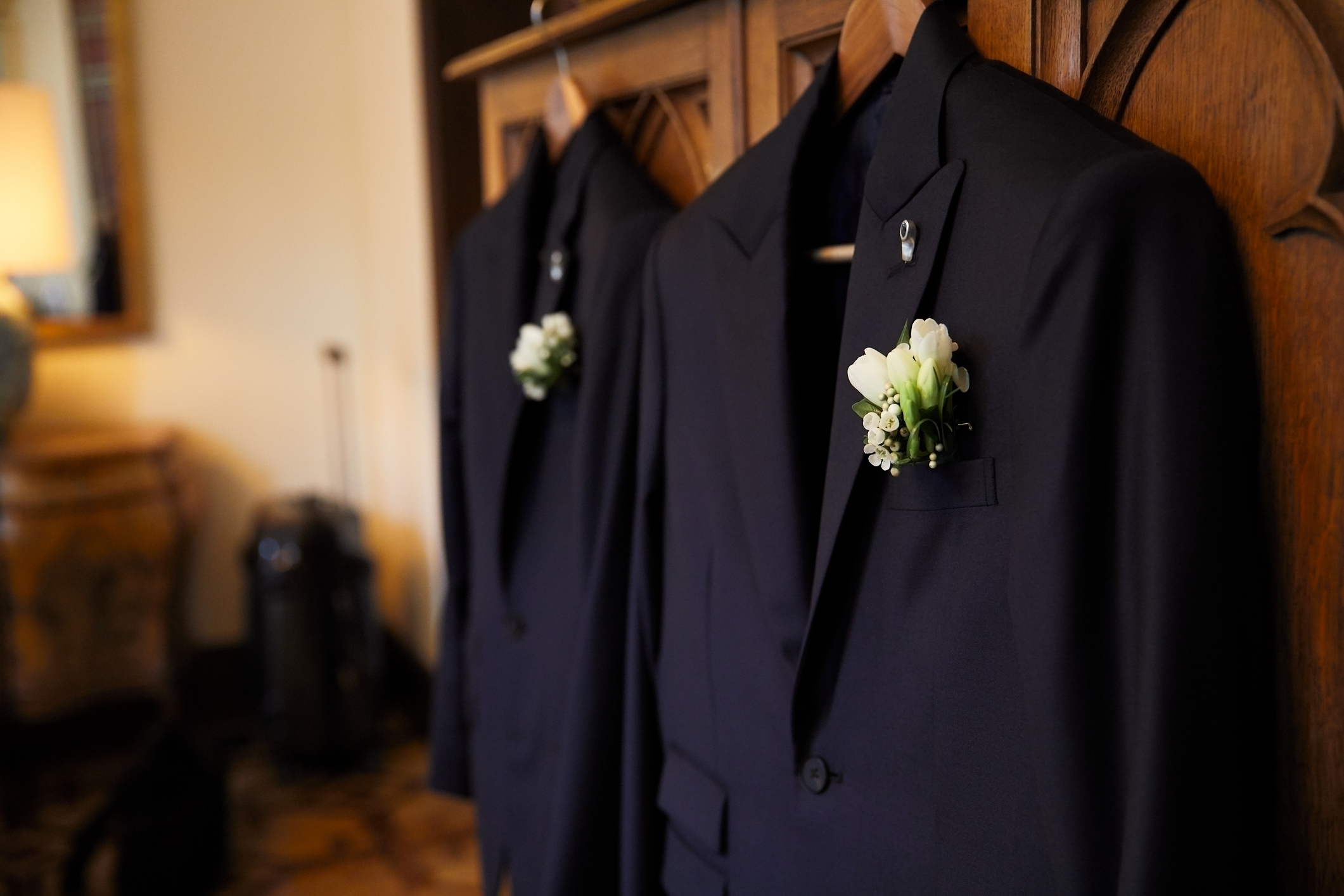 Two suits with white flower boutonnieres.