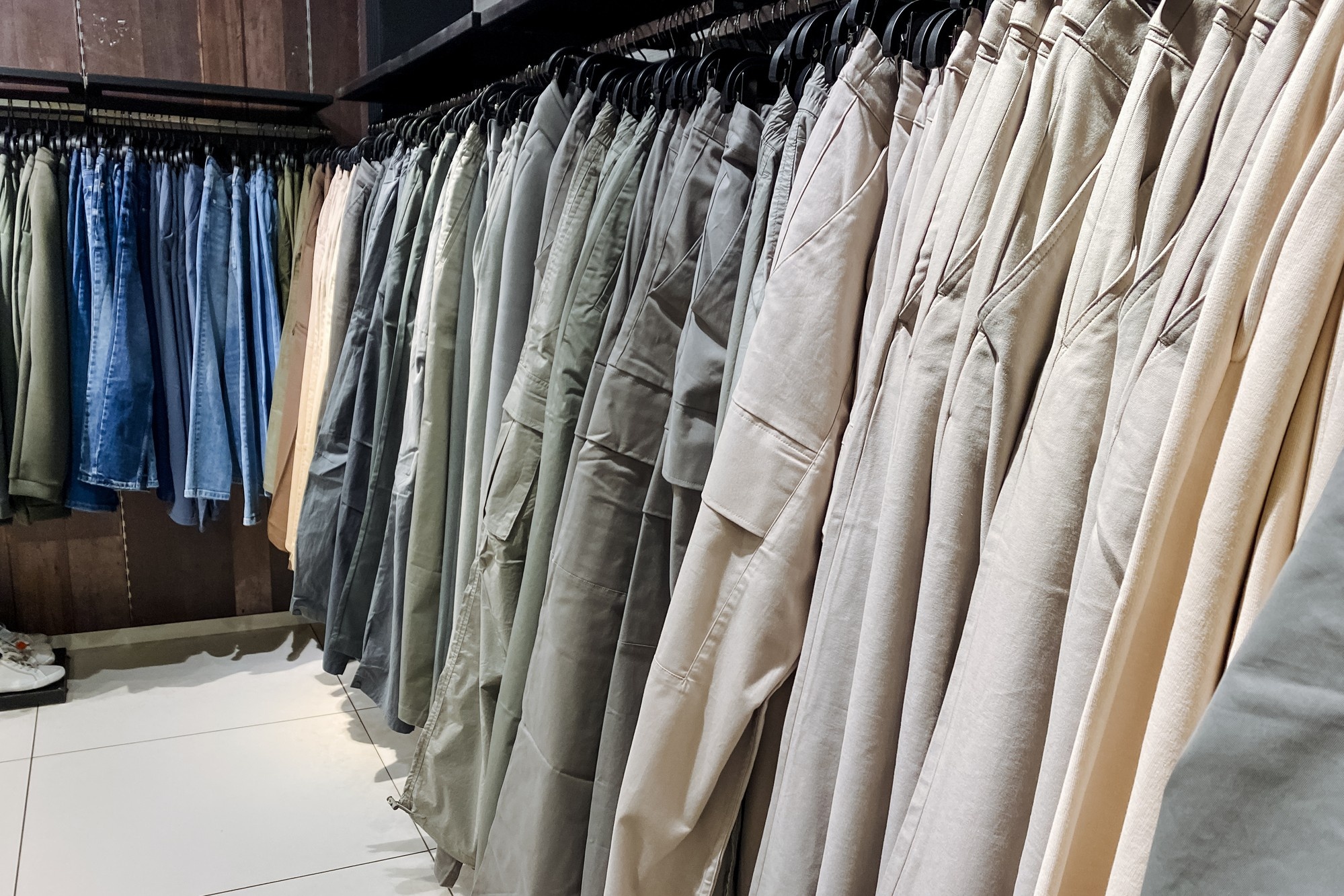 Clothing store rack with various pants displayed.