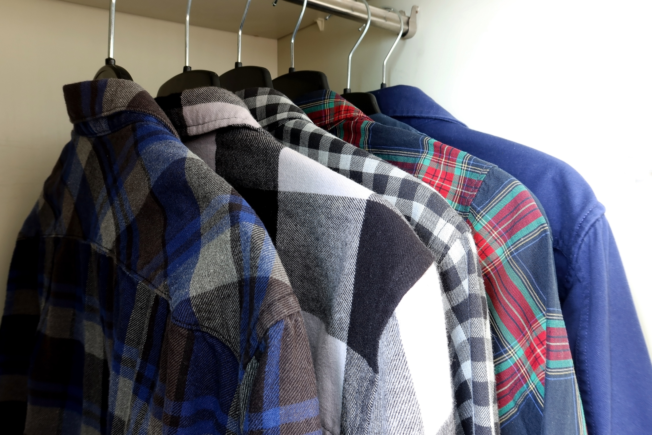 Plaid shirts hanging in a closet.