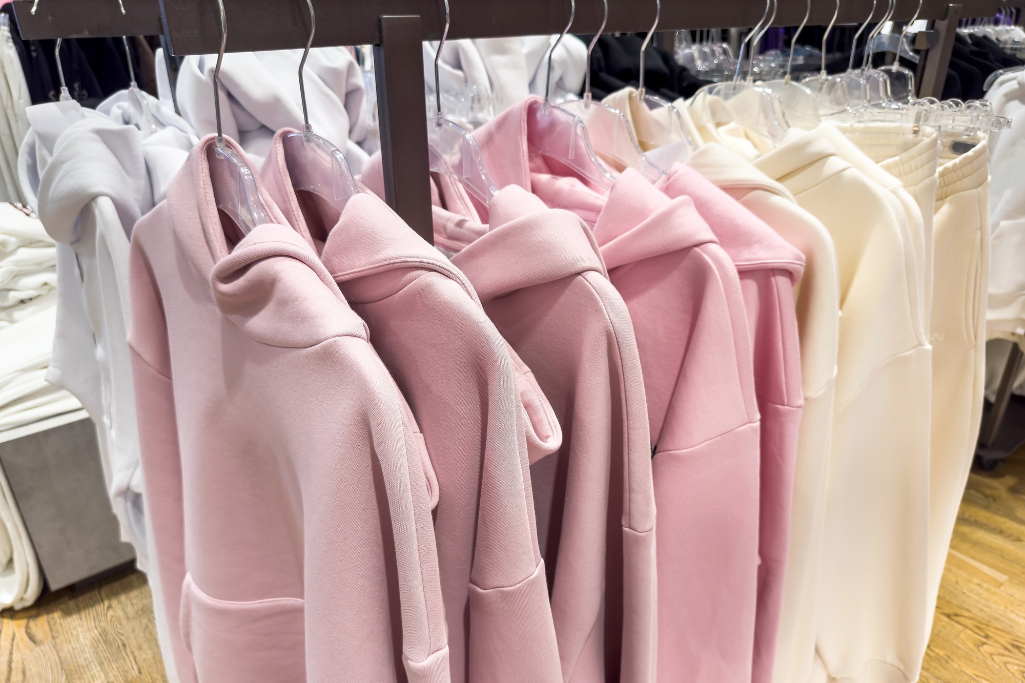 Pink hoodies hanging on a clothing rack.