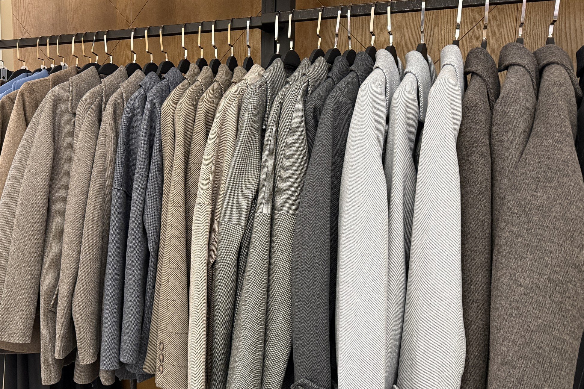 Row of gray and beige jackets hanging.