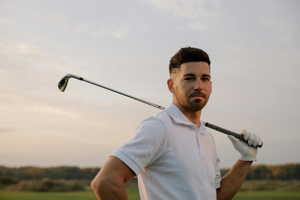 Golfer holding golf club over shoulder at sunset