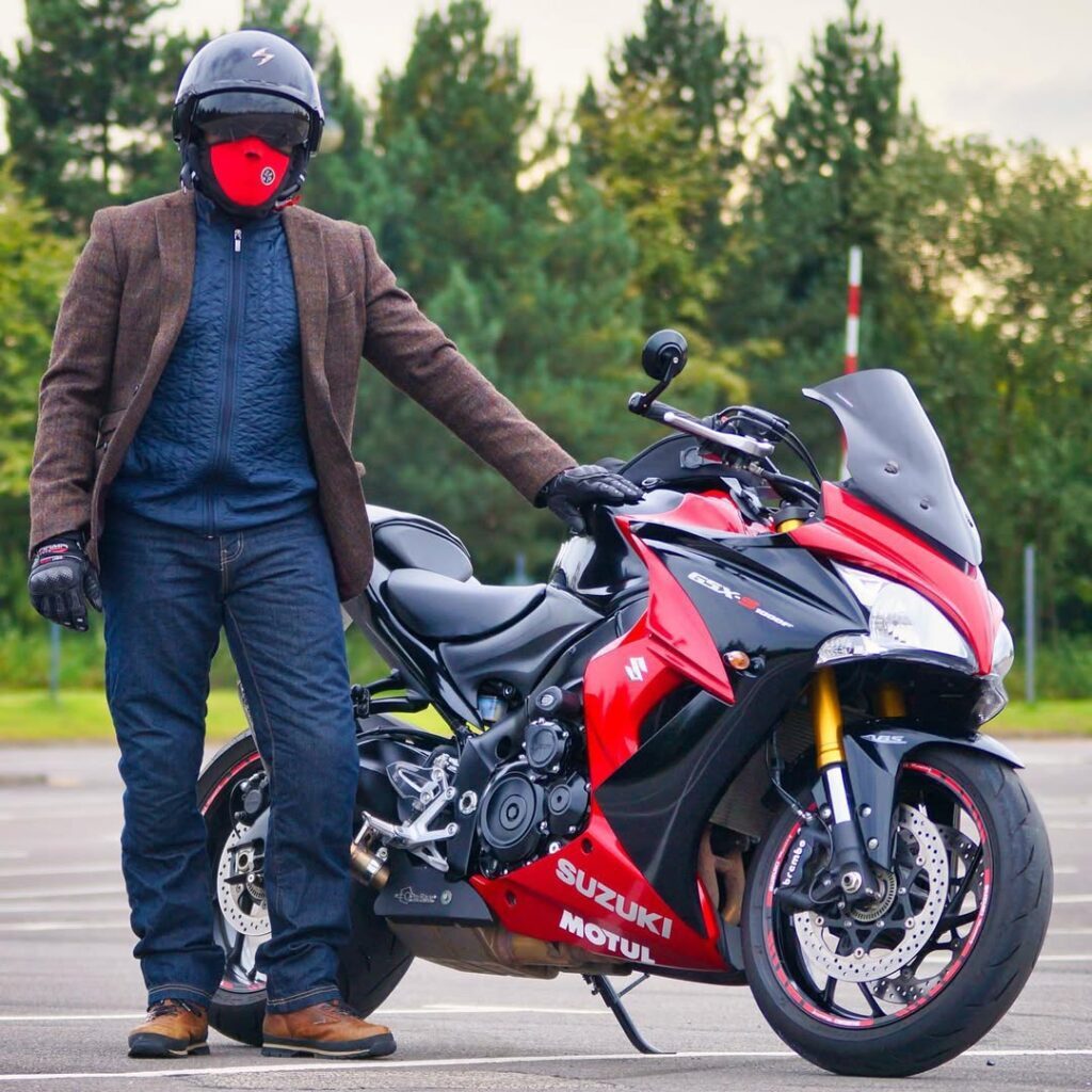 Rider in helmet beside red Suzuki sportbike