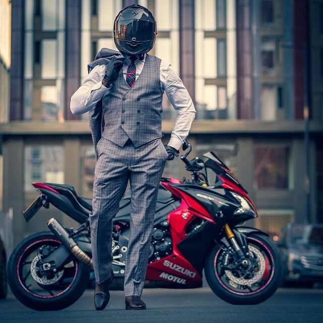 Person in suit and helmet beside red motorcycle