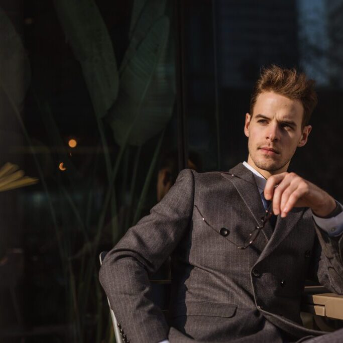 Man in suit sitting at outdoor cafe.